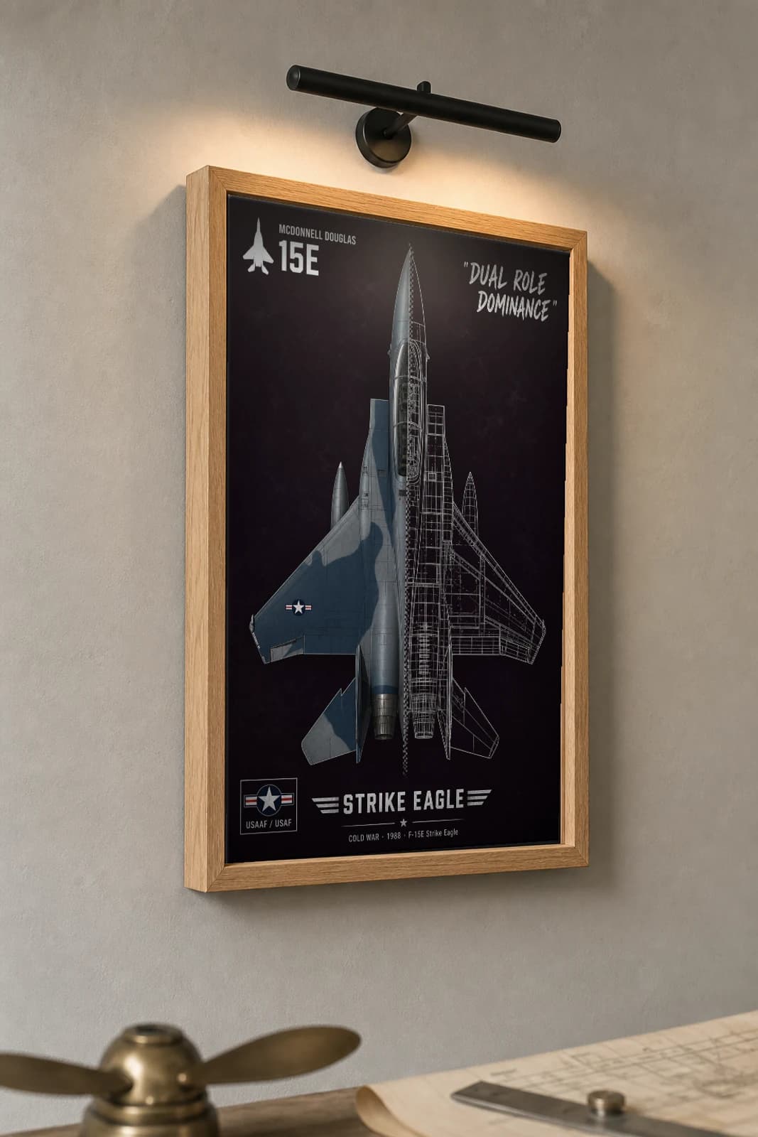 F-15 Strike Eagle Cutaway Poster — F-15E Cold War Split-View Blueprint Print — the framed print shown at a three-quarter angle on a styled gallery wall in a natural-oak frame