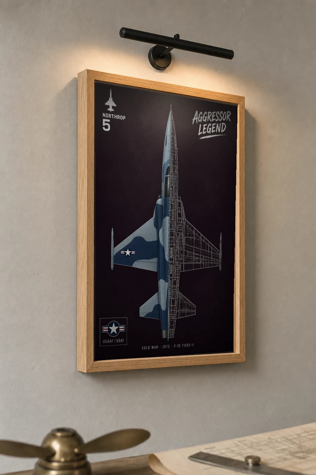 F-5E Tiger II Cutaway Poster — F-5E Cold War Split-View Blueprint Print — the framed print shown at a three-quarter angle on a styled gallery wall in a natural-oak frame