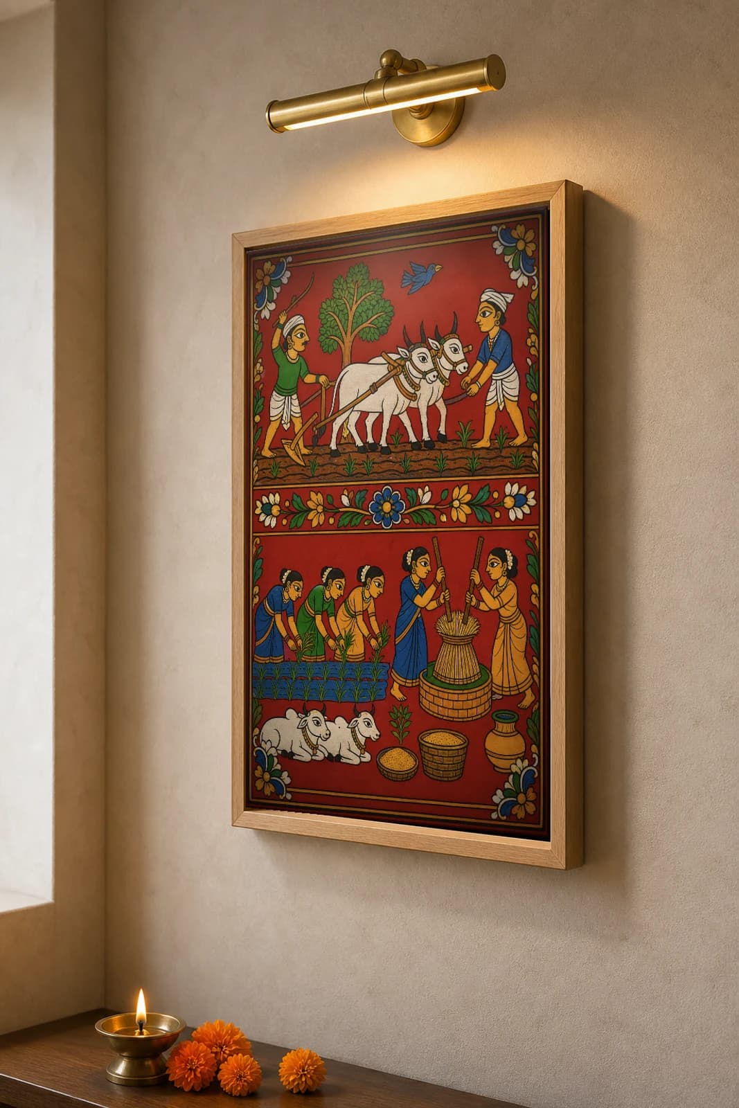 Vari Harvest Cheriyal Scroll Print — Telangana Paddy-Farming Life in Two Stacked Field Registers, Nakashi Folk Grammar on a Vermilion Ground — the framed print shown at a three-quarter angle on a styled gallery wall in a natural-oak frame