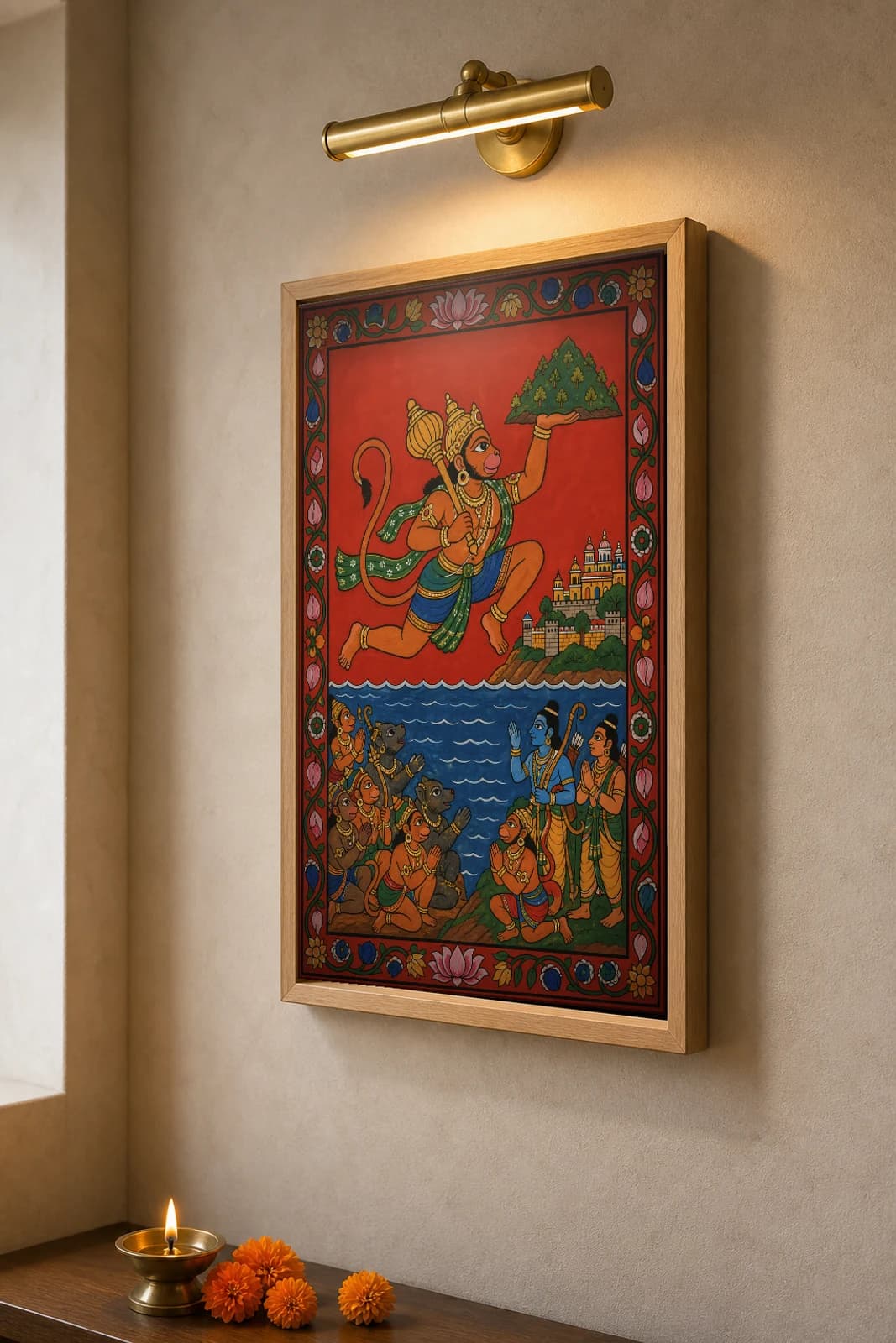 Hanuman Leap Cheriyal Scroll Print — Hanuman in Flight Over the Ocean to Lanka in Nakashi Folk Grammar on a Vermilion Ground — the framed print shown at a three-quarter angle on a styled gallery wall in a natural-oak frame