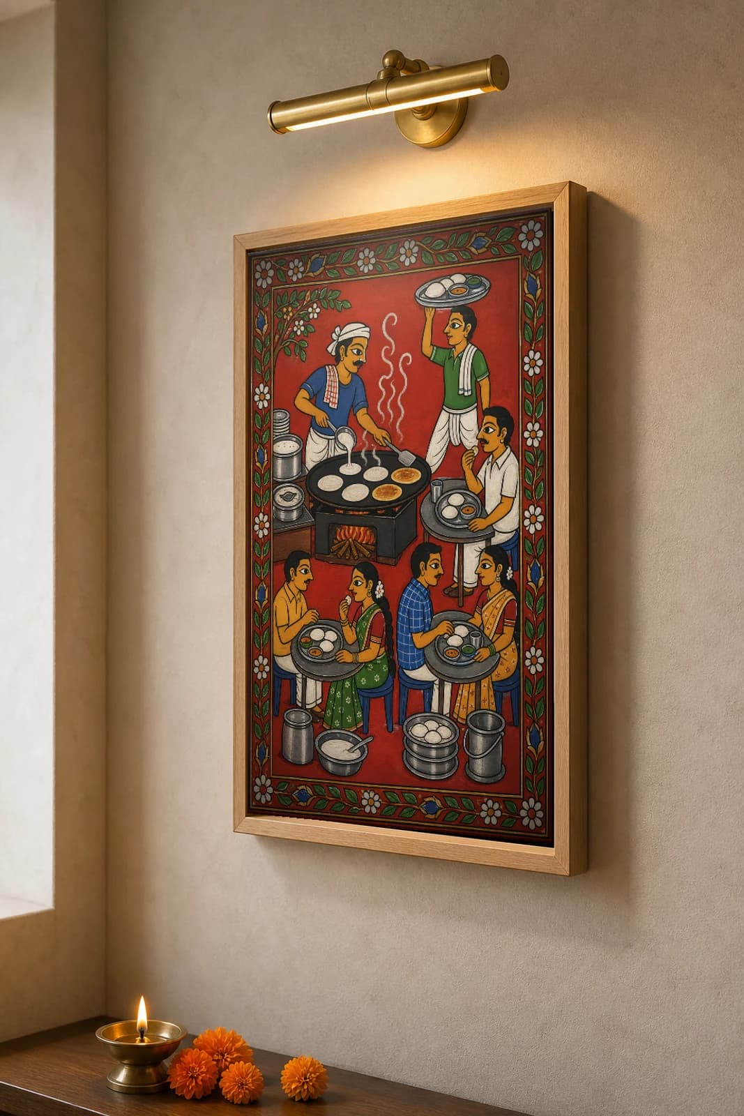 Tiffin Centre Cheriyal Fusion Print — A Morning Idli-Dosa Tiffin Centre in Full Swing, Nakashi Folk Grammar on a Vermilion Ground — the framed print shown at a three-quarter angle on a styled gallery wall in a natural-oak frame