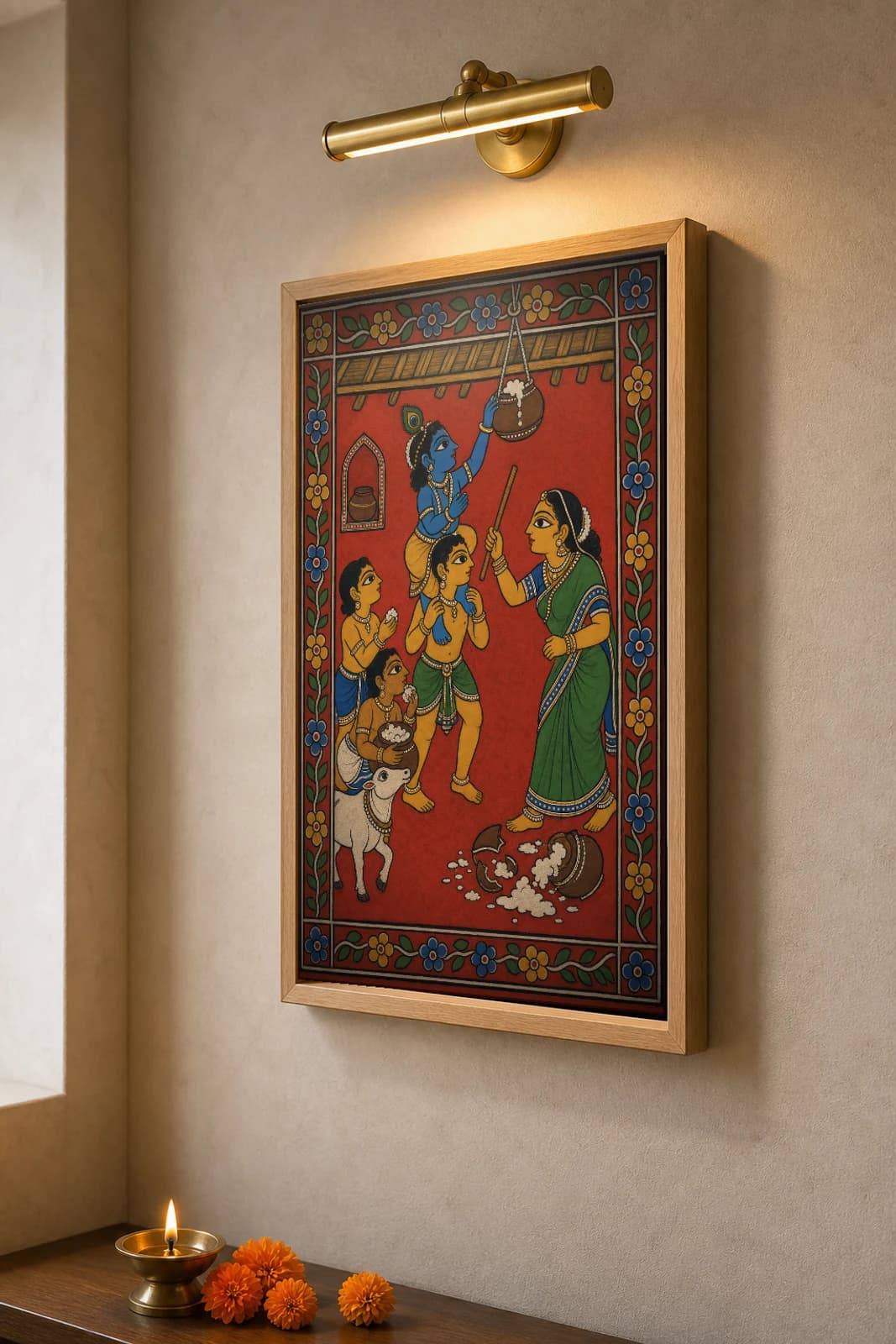 Makhan Chor Cheriyal Scroll Print — Baby Krishna Stealing Butter as Yashoda Approaches, Nakashi Folk Grammar on a Vermilion Ground — the framed print shown at a three-quarter angle on a styled gallery wall in a natural-oak frame