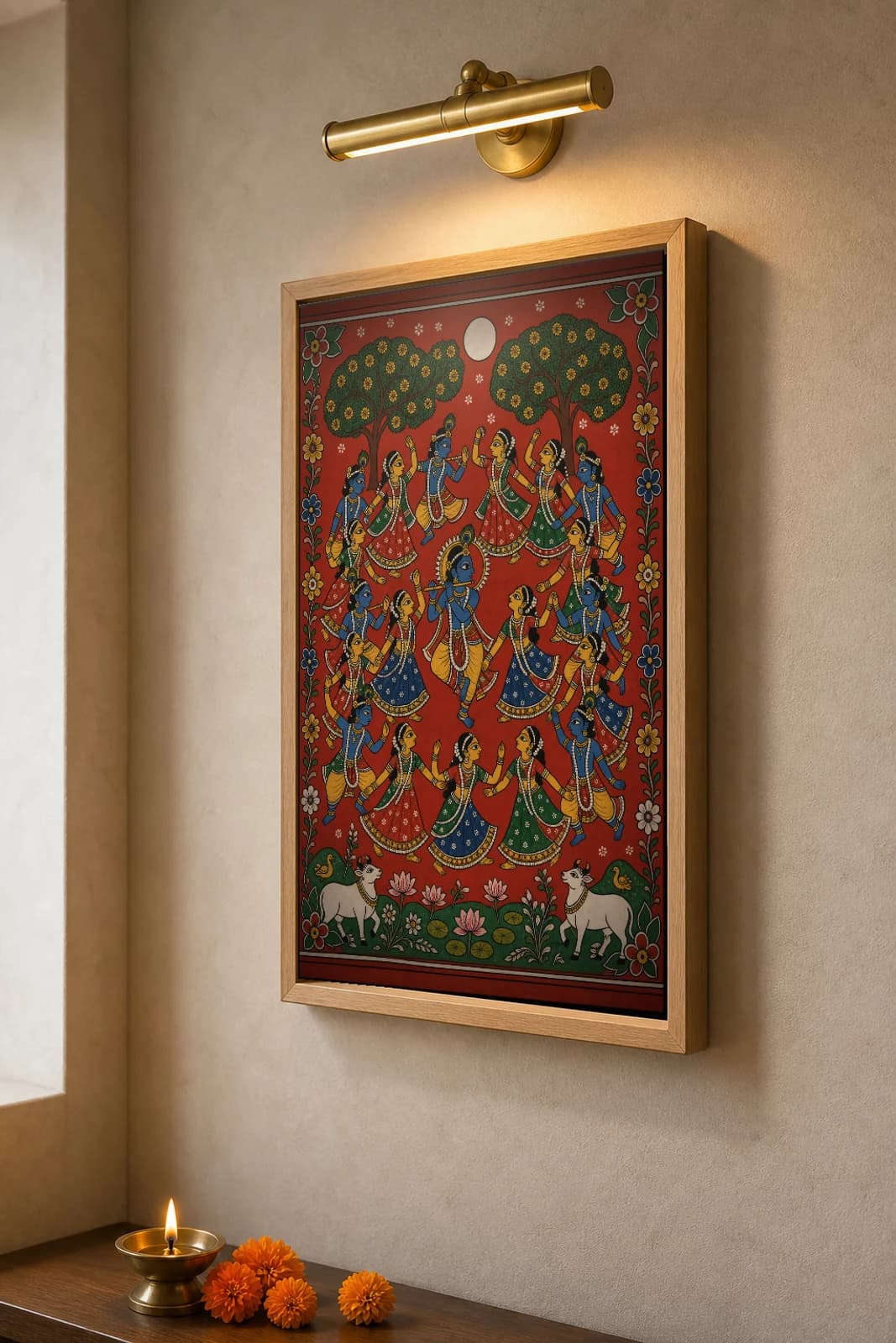 Rasa Lila Cheriyal Scroll Print — Krishna's Autumn-Moon Circle Dance with the Gopis, Nakashi Folk Grammar on a Vermilion Ground — the framed print shown at a three-quarter angle on a styled gallery wall in a natural-oak frame
