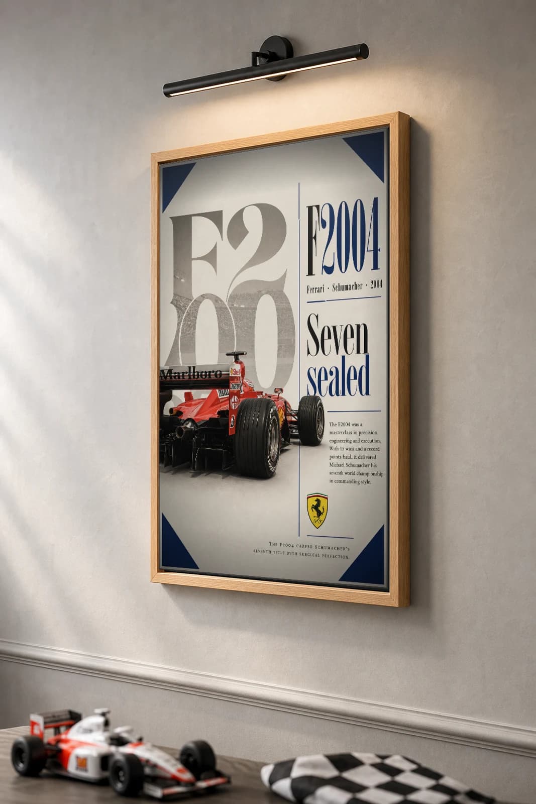 Michael Schumacher — Ferrari F2004 perfection Poster — 2004 F1 Grid Editorial Wall Art · framed A2 — the framed print shown at a three-quarter angle on a styled gallery wall in a natural-oak frame