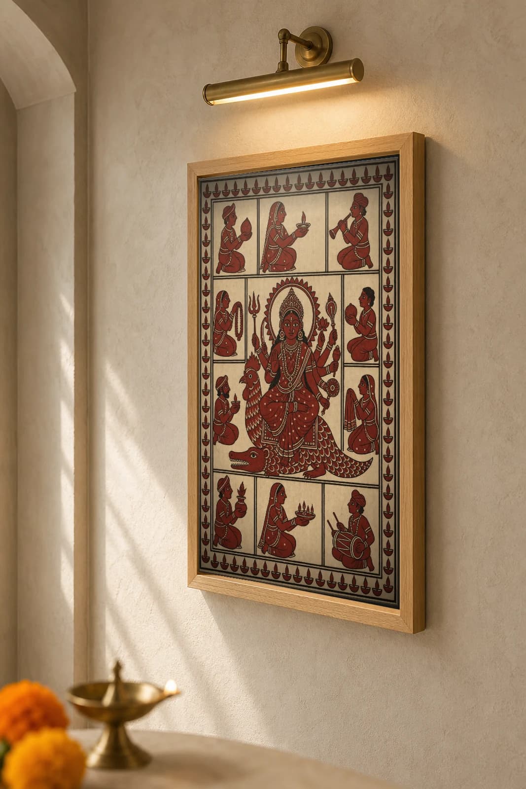 Devotee Offerings — Mata ni Pachedi shrine-cloth art print · the enthroned goddess ringed by panels of kneeling worshippers bearing coconut, lamp and garland · madder-red, iron-black, warm cream cotton · collector edition — the framed print shown at a three-quarter angle on a styled gallery wall in a natural-oak frame