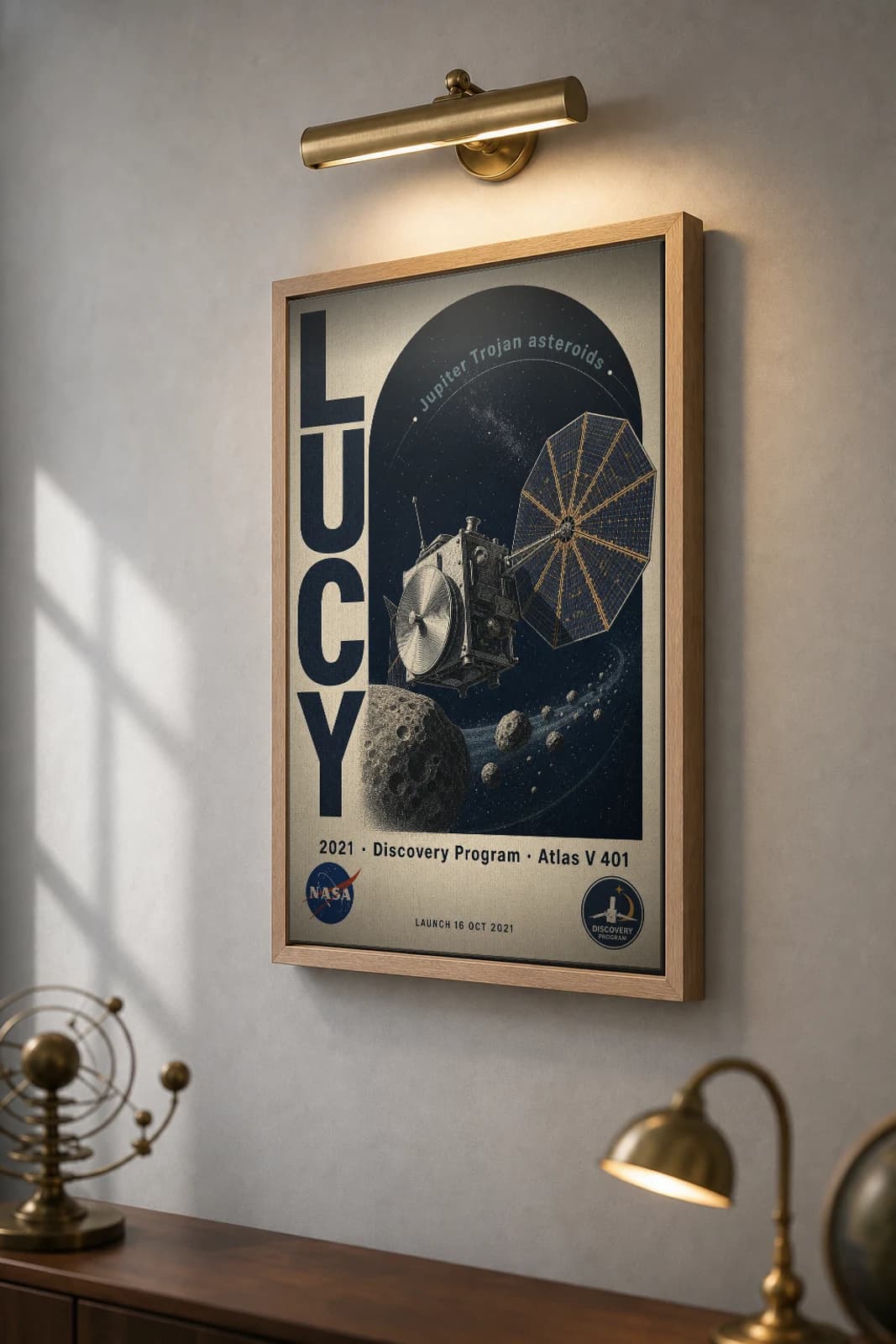 Lucy Poster — 2021 Atlas V 401 NASA Heritage Collector Print — the framed print shown at a three-quarter angle on a styled gallery wall in a natural-oak frame
