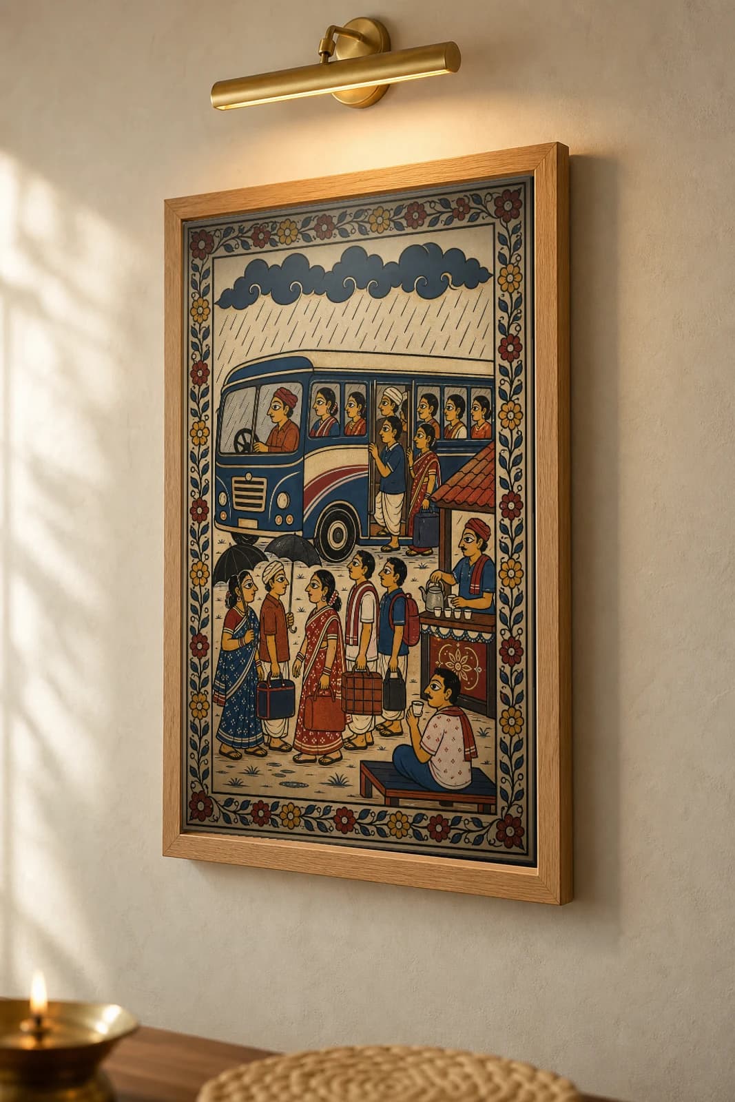 Monsoon Bus Stand Pattachitra Print — an Odisha bus halt in the rain, passengers and a chai stall in patta line · collector edition A2 · contemporary fusion — the framed print shown at a three-quarter angle on a styled gallery wall in a natural-oak frame