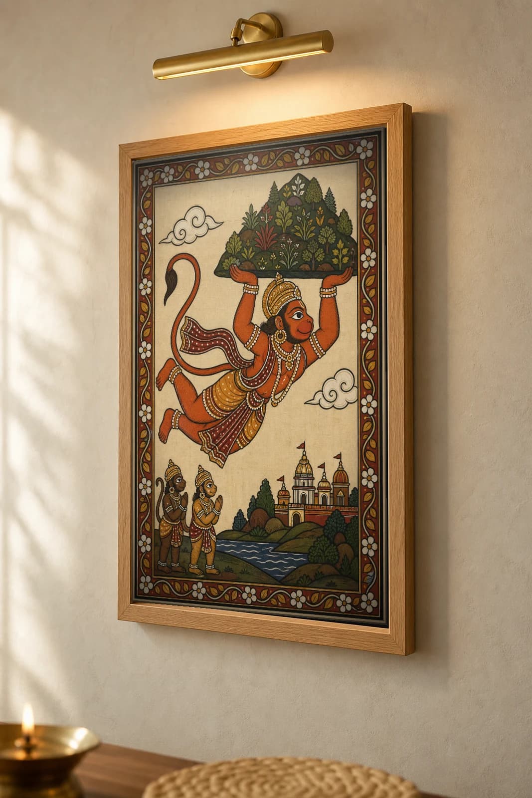 Hanuman Sanjivani Pattachitra Print — Hanuman flying with the healing mountain overhead · collector edition A2 · classical Odisha cloth-painting grammar — the framed print shown at a three-quarter angle on a styled gallery wall in a natural-oak frame
