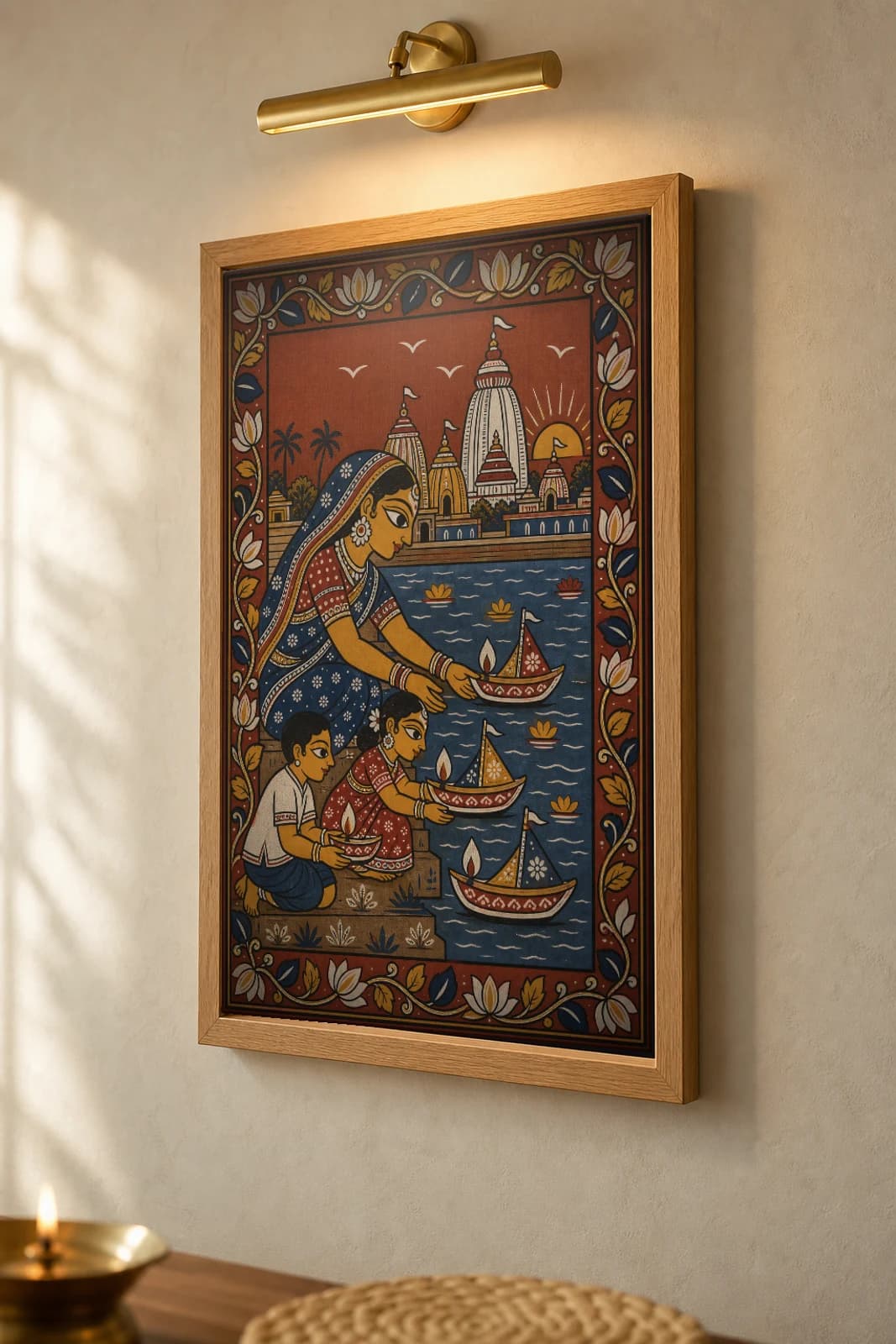Boita Bandana Pattachitra Print — a family floating lamp-boats at dawn on Kartik Purnima · collector edition A2 · contemporary fusion — the framed print shown at a three-quarter angle on a styled gallery wall in a natural-oak frame
