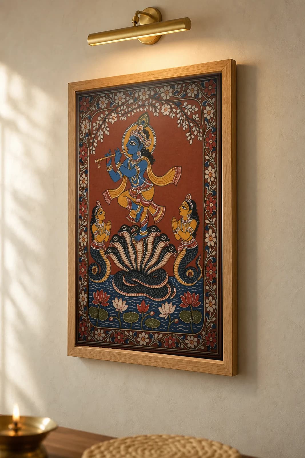 Kaliya Daman Pattachitra Print — Krishna dancing on the serpent Kaliya in Odisha cloth-painting grammar · collector A2 · Krishna leela — the framed print shown at a three-quarter angle on a styled gallery wall in a natural-oak frame