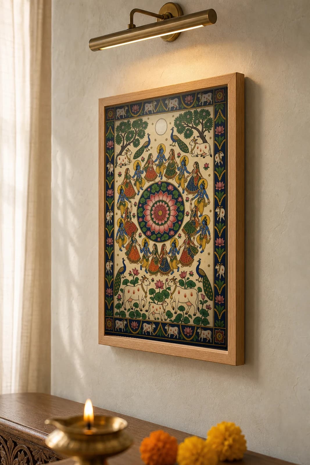 Raas Mandala Pichwai-Style Print — gopis and Krishna dancing in concentric rings around a central lotus under a full moon, with cows and a lotus pond below, on warm cream cloth — the framed print shown at a three-quarter angle on a styled gallery wall in a natural-oak frame