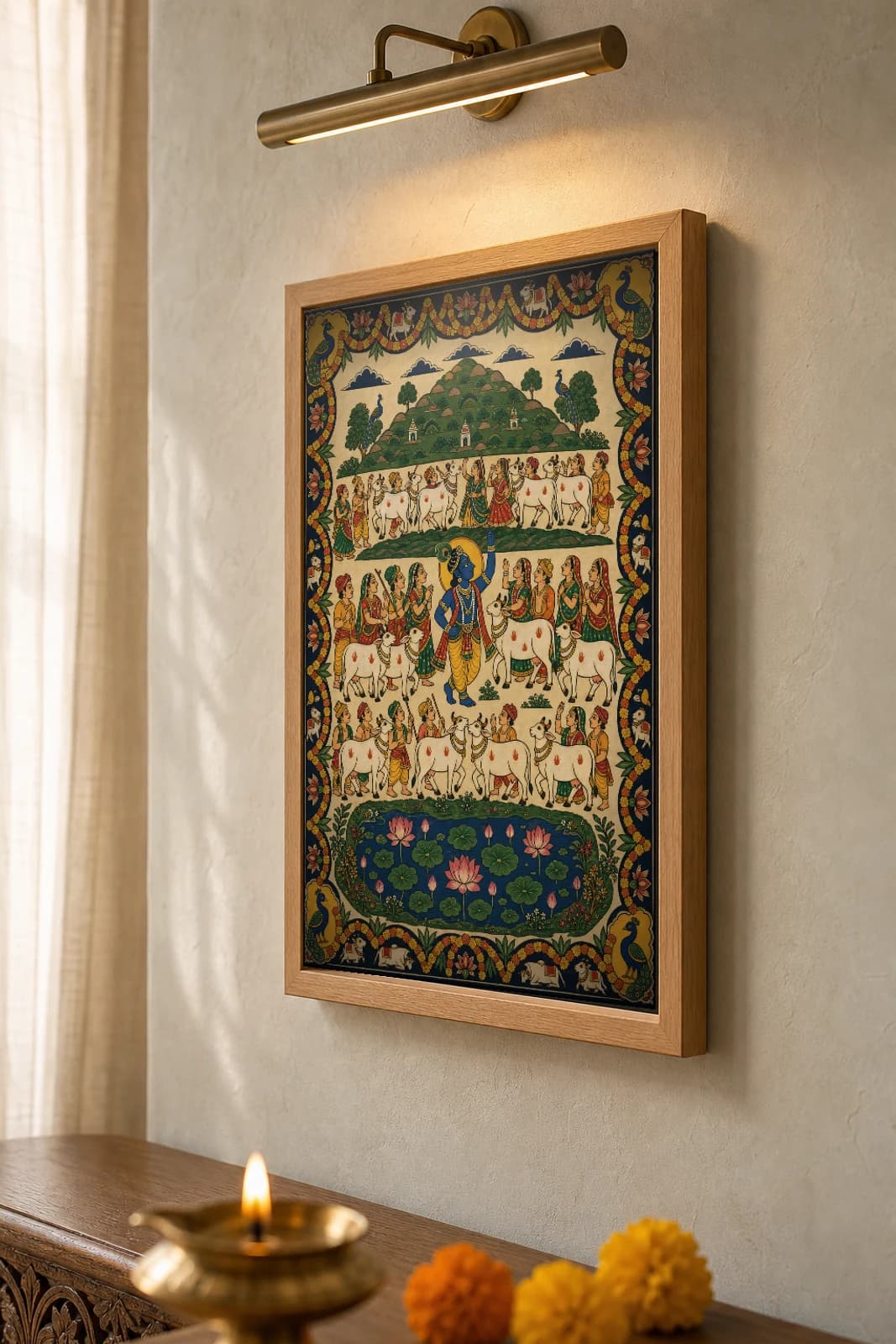 Govardhan Parikrama Pichwai-Style Print — pilgrims and cows circling Mount Govardhan with a flute Krishna at centre and a lotus pond, on warm cream cloth — the framed print shown at a three-quarter angle on a styled gallery wall in a natural-oak frame
