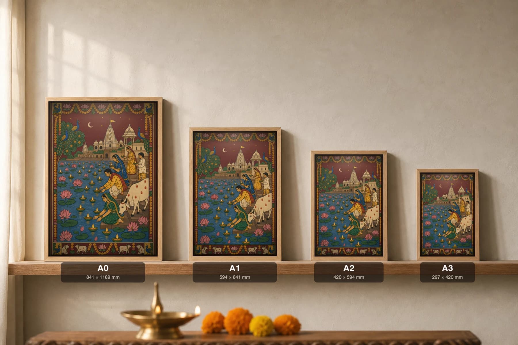 Deep-Daan Pichwai-Style Print — a family floating oil lamps on a lotus river at night before a temple-town under a crescent moon, with a cow, on deep maroon night cloth — print size guide showing the artwork at A0, A1, A2 and A3 in natural-oak frames at true relative scale