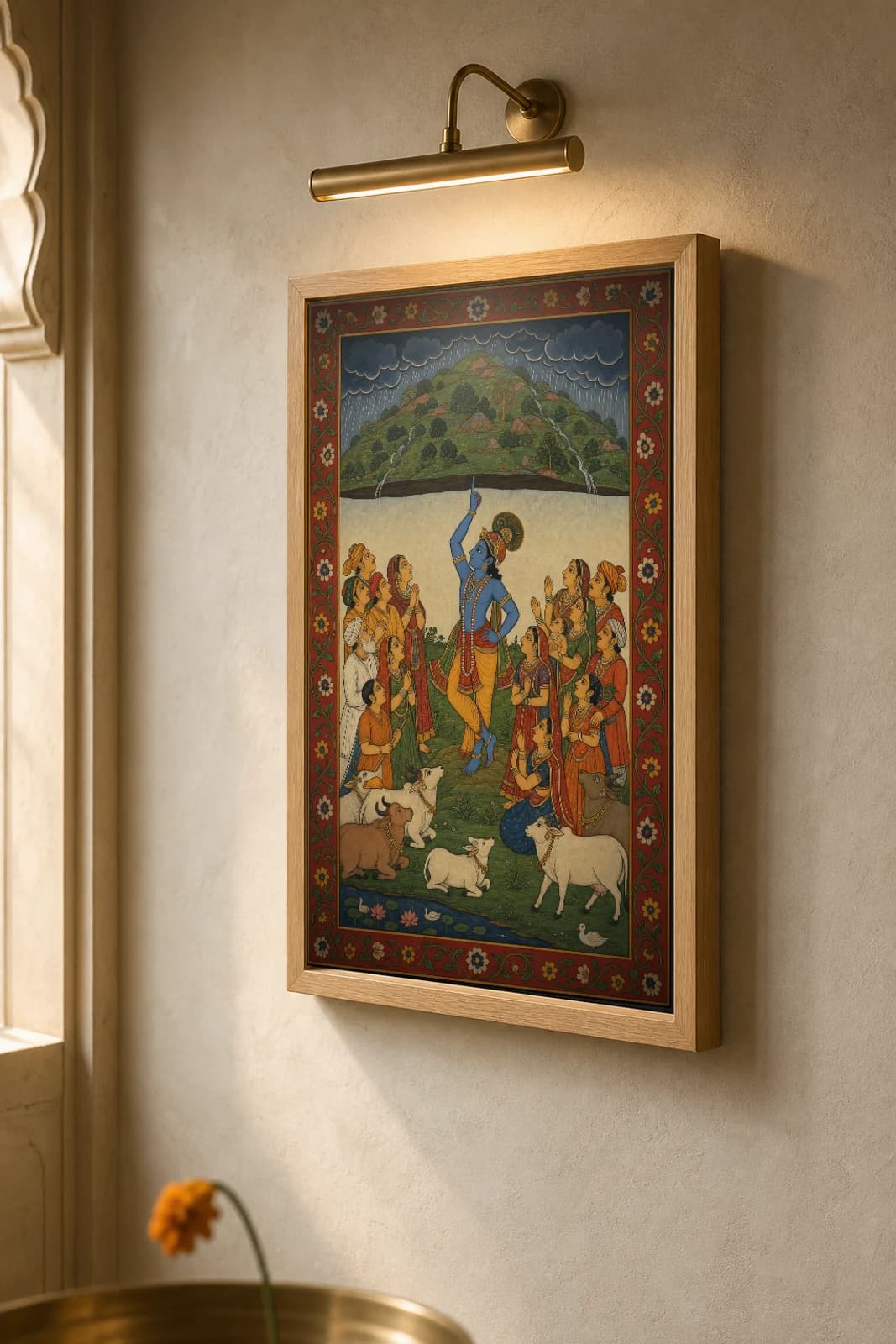 Govardhan Rajput Miniature Print — Mewar Krishna-lila, Krishna lifting the hill on one finger against the storm · collector edition A2 — the framed print shown at a three-quarter angle on a styled gallery wall in a natural-oak frame
