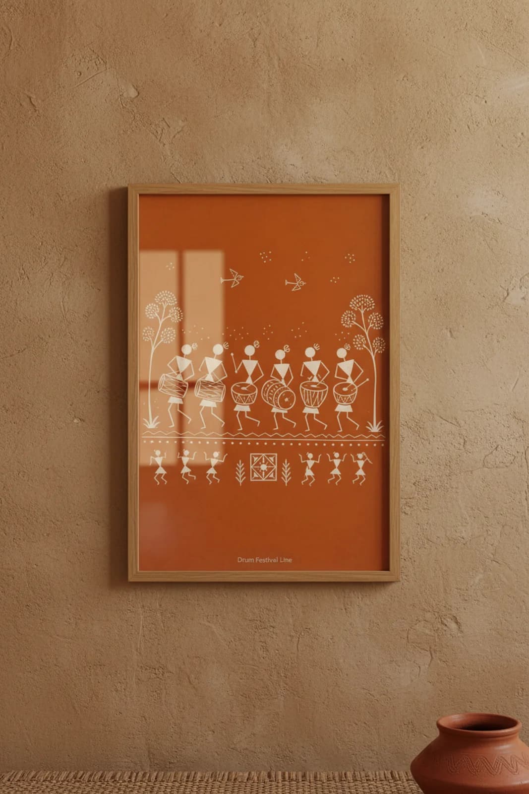 Drum Festival Line Warli print in natural oak A2 frame on warm-earth-neutral mud-plaster wall — rustic Indian folk art mockup