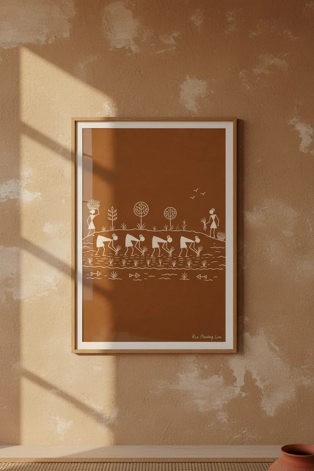 Rice Planting Line Warli print in natural oak A2 frame on warm-earth-neutral mud-plaster wall — rustic Indian folk art mockup