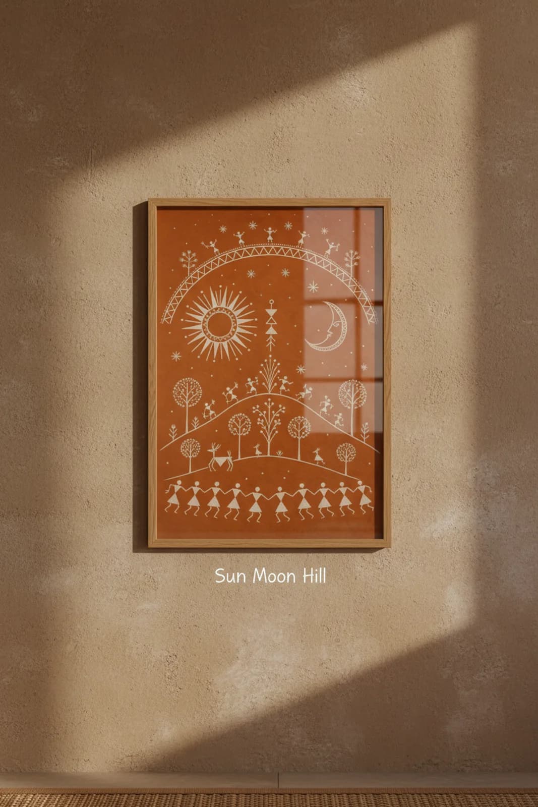 Sun Moon Hill Warli print in natural oak A2 frame on warm-earth-neutral mud-plaster wall — rustic Indian folk art mockup