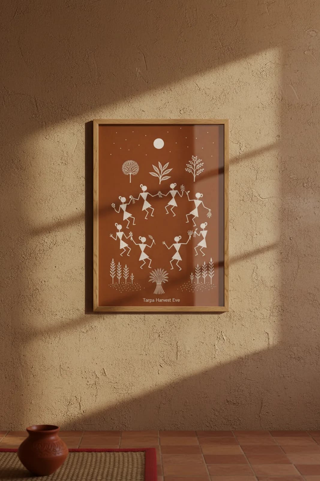 Tarpa Harvest Eve Warli print in natural oak A2 frame on warm-earth-neutral mud-plaster wall — rustic Indian folk art mockup
